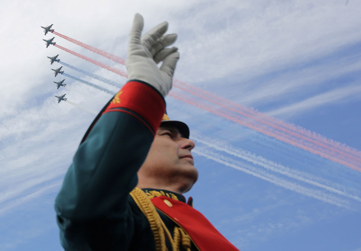 A member of a military band performs as Russian fighter jets fly in formation during the Navy Day parade in Kronshtadt, a seaport town in the suburb of St. Petersburg