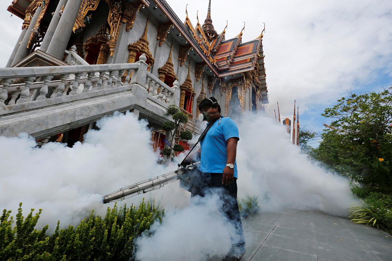 A city worker fumigates the area to control the spread of mosquitoes at a temple in Bangkok