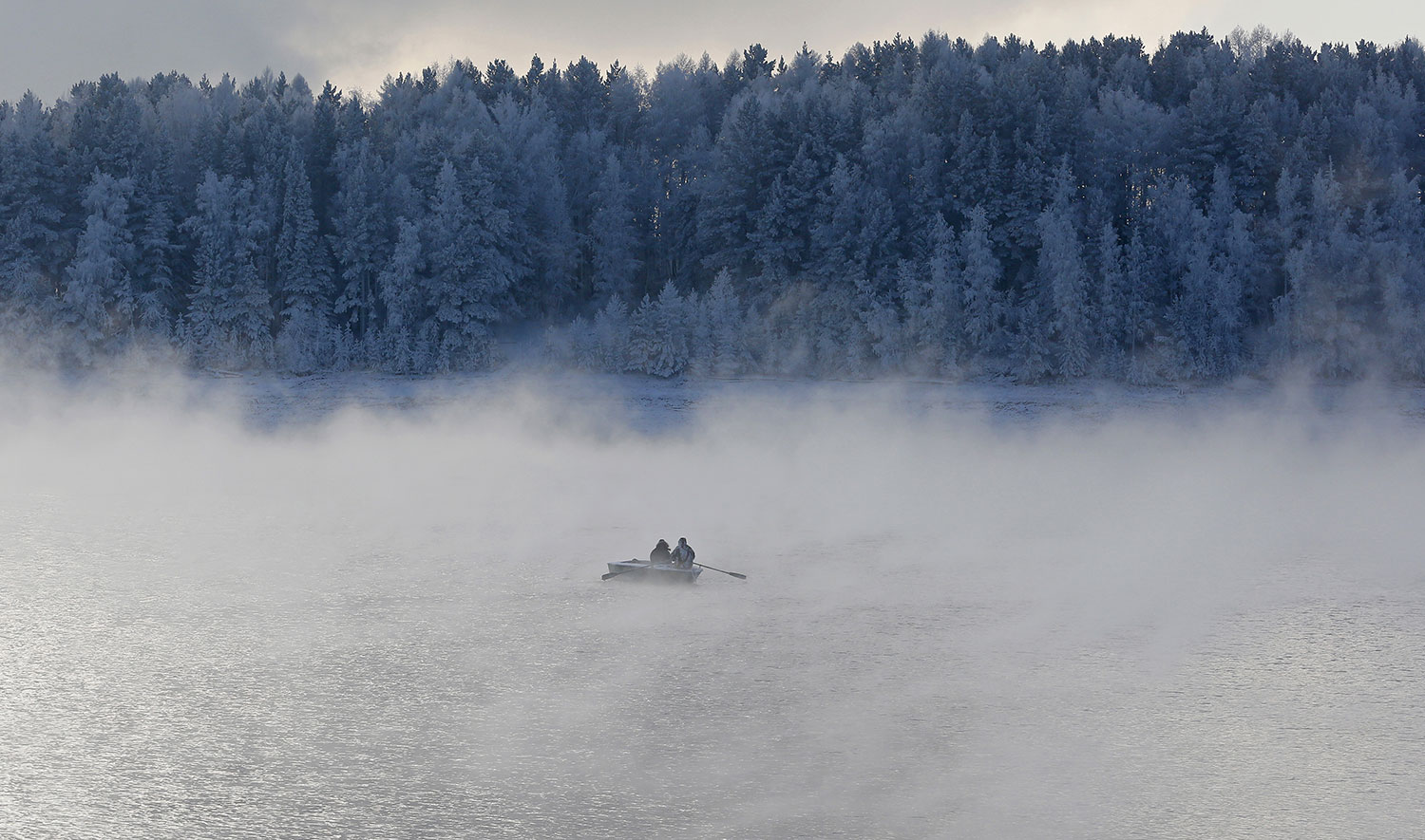 Two men row a boat through a frosty fog along the Yenisei River at air temperature some minus 20 degrees Celsius in the Taiga district outside the Siberian city of Krasnoyarsk, Russia