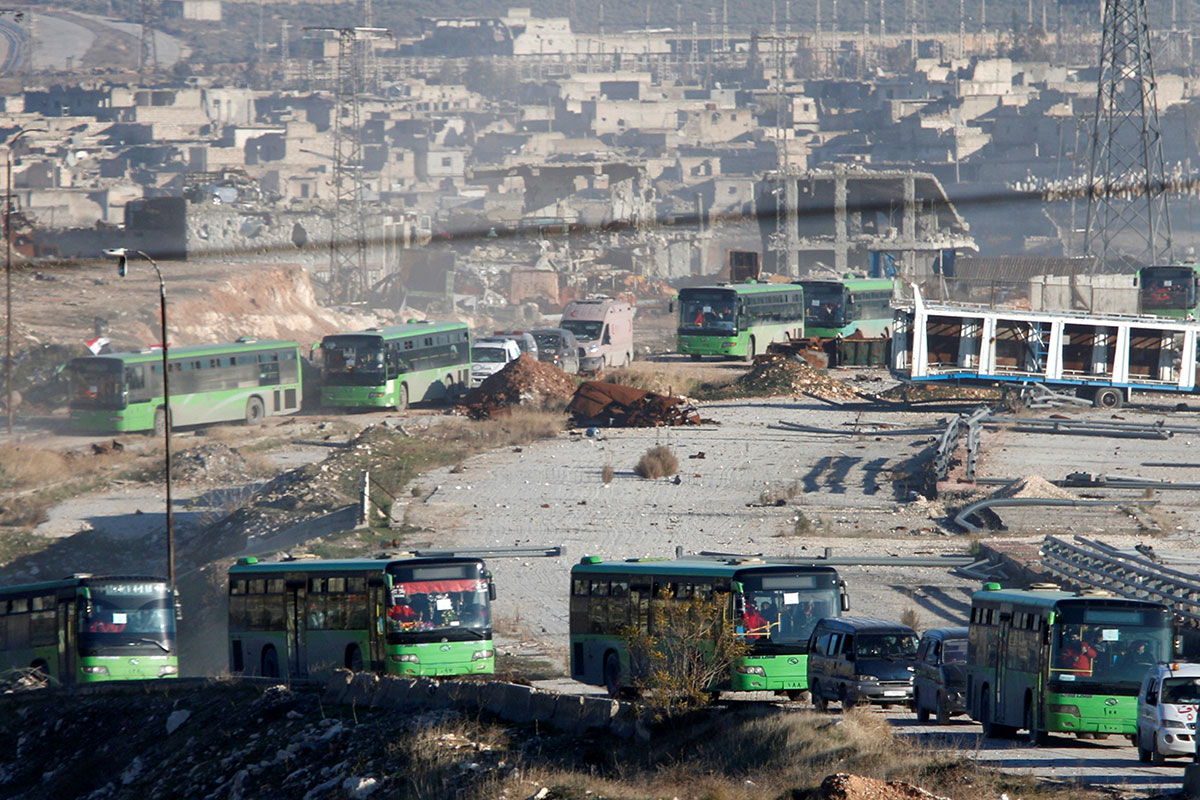 Ambulances and buses evacuating people drive out of a rebel-held part of Aleppo