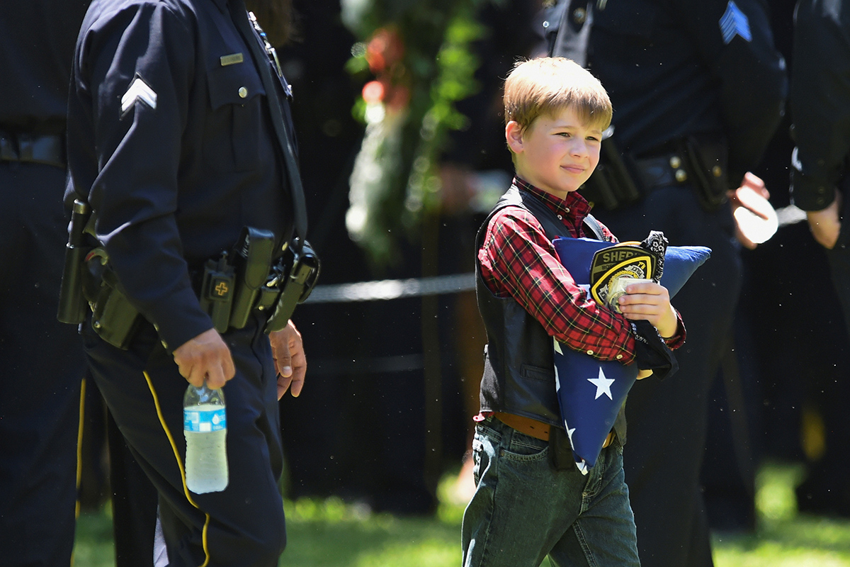 Magnus Ahrens carries a folded U.S. flag after the burial ceremony for his father, Dallas Police Department Senior Corporal Lorne B. Ahrens, who was among five police officers shot dead the previous week, at Restland Public Safety Memorial Gardens