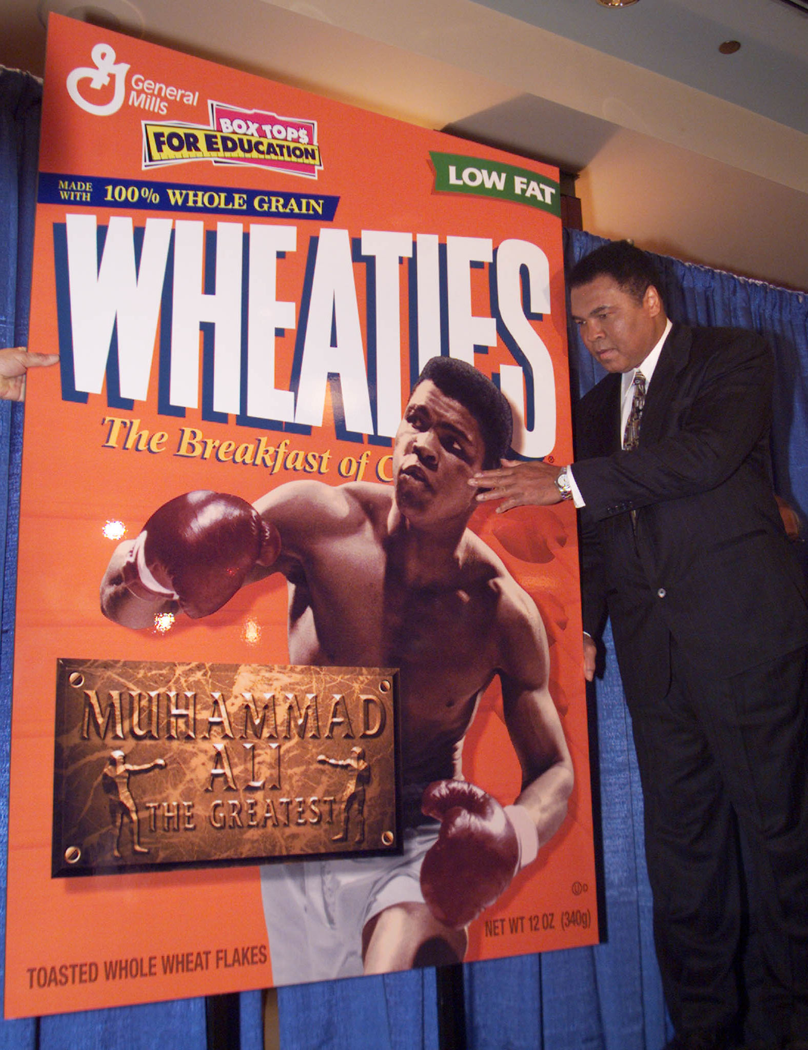 Three-time heavyweight boxing champion Muhammad Ali poses with an enlarged copy of a new Wheaties ce..