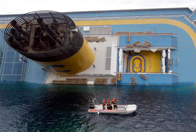 Rescuers stand in a boat next to the ship. Emergency workers want to search 1,500 cabins as well as the ship's public spaces, including eight bars, five restaurants, four swimming pools, and a casino, according to CNN. 