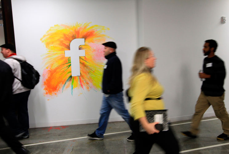 Employees walk past the company logo. 