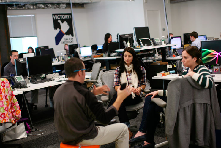 Employees gather in their work environment for a discussion.  