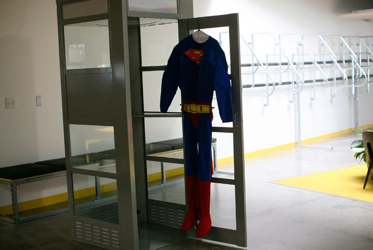 A superman costume hangs at a telephone booth for private cell phone discussions.   