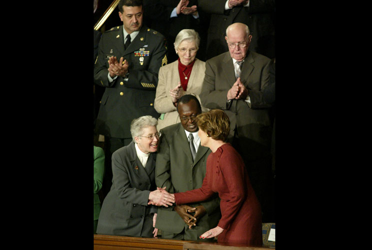 First lady Laura Bush (R) shakes hands with Sister Maria Fest (L) from the Catholic Nuns in Service as special guest Peter Mugyeni, director of the Joint Clinical Research Center in Uganda, stands between them during President George W. Bush's State of th