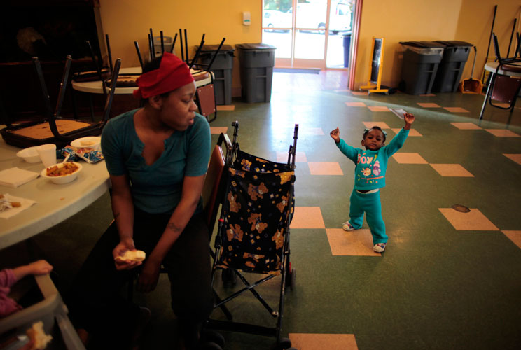 Denise Bowie (L), 21, watches her one-year-old daughter Genelle practise walking in the dining area. 