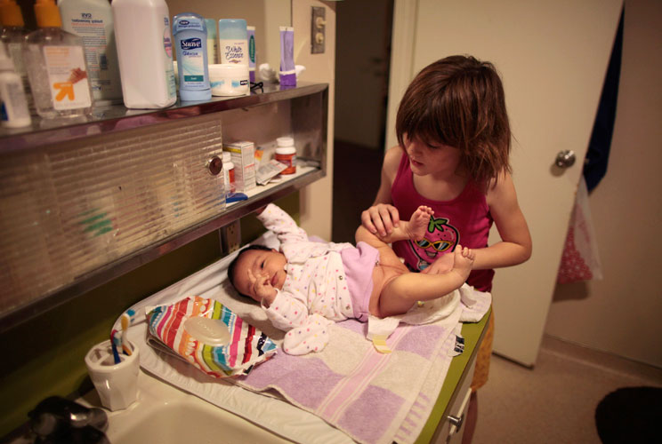 Lilly Earp, 8, changes the diaper of her five-week-old sister Emily in their apartment at the shelter. 