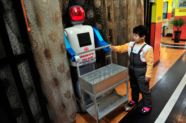 		<p>A boy touches a robot that specialises in delivering drinks at the Robot Restaurant.</p>