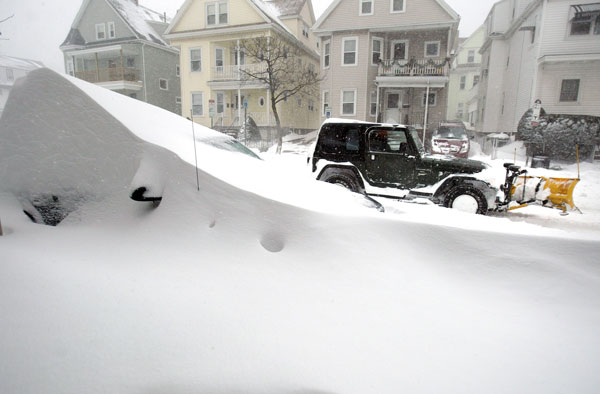 		<p>A vehicle equipped with a snow plow passes a car covered in snow in Somerville, Massachusetts January 23, 2005. A Blizzard which started last night covered the Boston area with as much as two feet of snow, causing the city to declare a snow emergency