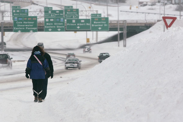 		<p>High snowbanks make sidewalks unusable to a couple who resorted to walking along highway 111 in Dartmouth, Nova Scotia on January 24, 2005. The region was hit by a third snowstorm within a period of one week, resulting in stoppages of all public tran