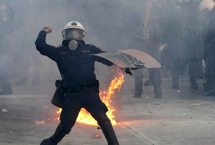 A riot police officer throws a stone at demonstrators during violent protests in Athens' Syntagma (Constitution) square February 12, 2012.