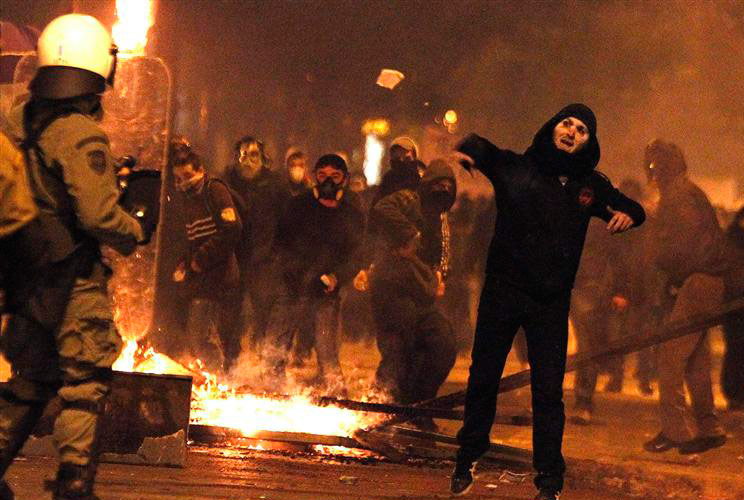 A protester hurls rocks at police during a violent anti-austerity demonstration in central Athens February 12, 2012. 