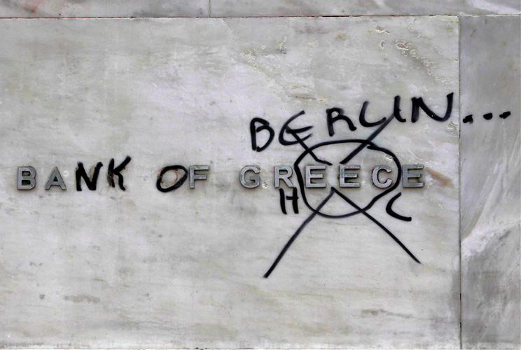 A defaced Bank of Greece sign is seen during protests against planned reforms by Greece's coalition government in Athens, February 10, 2012.