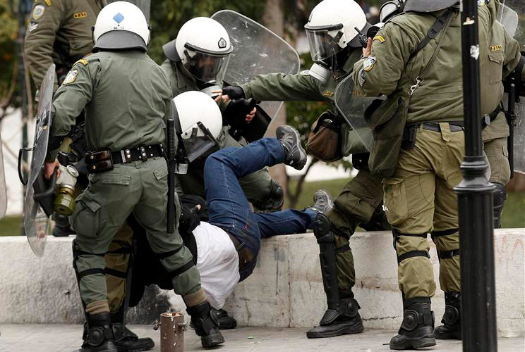 Riot police grapple with a demonstrator during protests against planned reforms by Greece's coalition government in Athens, February 10, 2012. 