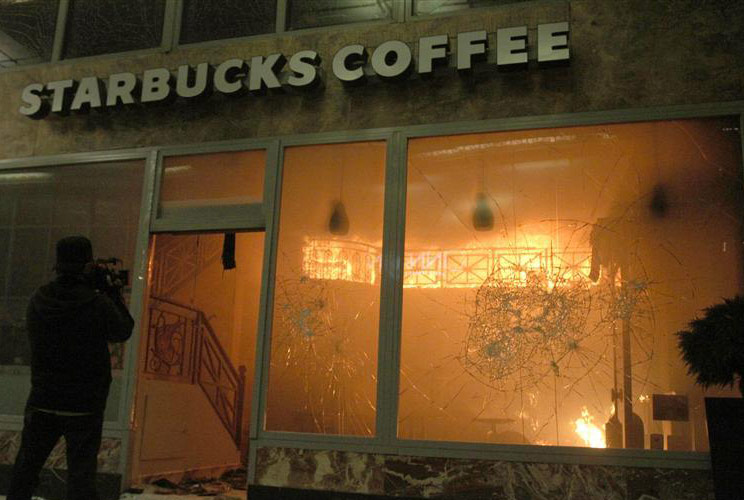 A cameraman films a Starbucks coffee shop in flames during violent protests in central Athens, February 12, 2012. 