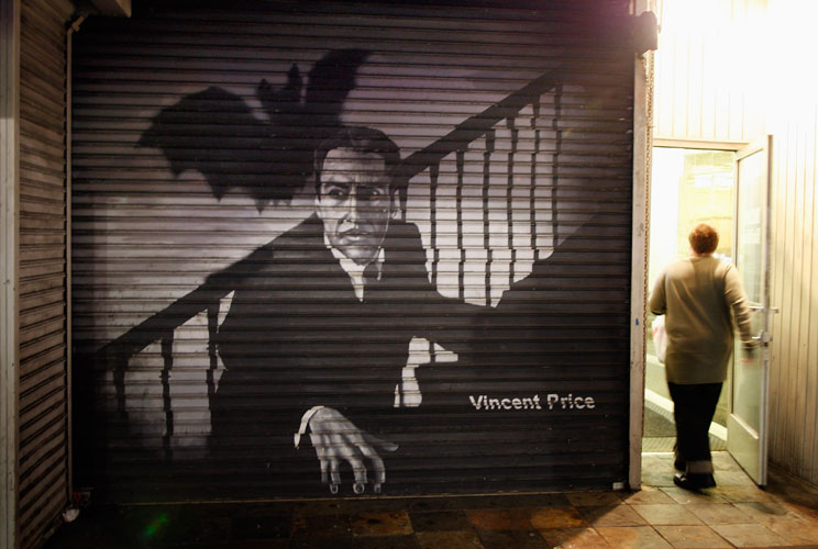 A person enters a door next to an image of horror movie actor Vincent Price on the security door of a business on Hollywood Boulevard.