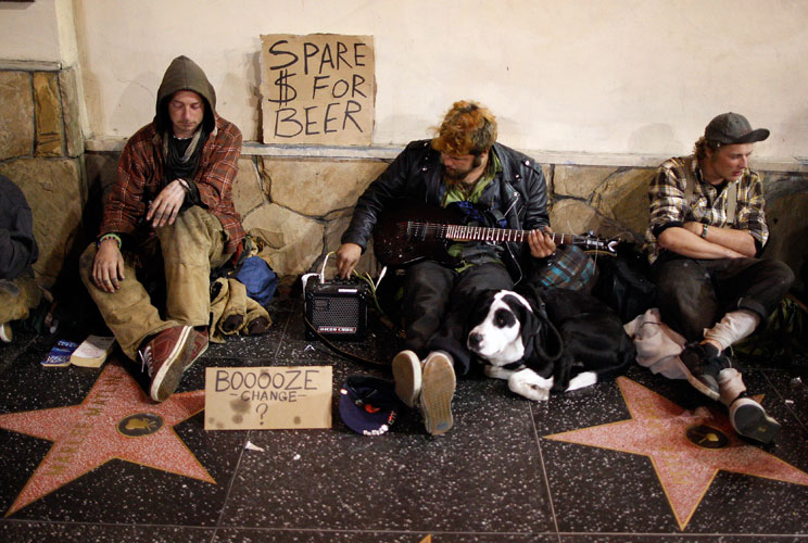 Homeless men sitting on Hollywood Walk of Fame stars on Hollywood Boulevard beg for money to buy beer.