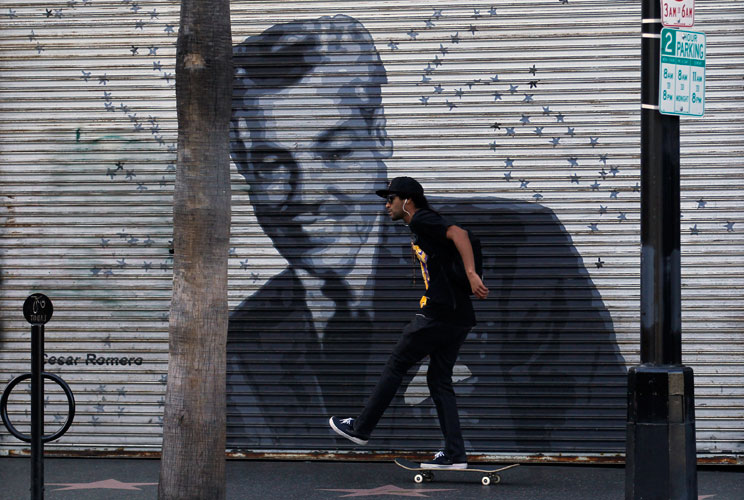 A skateboarder pushes past a closed store front along Hollywood Boulevard.