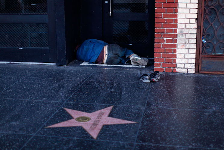 A homeless man sleeps in a doorway in the early morning hours along Hollywood Boulevard.