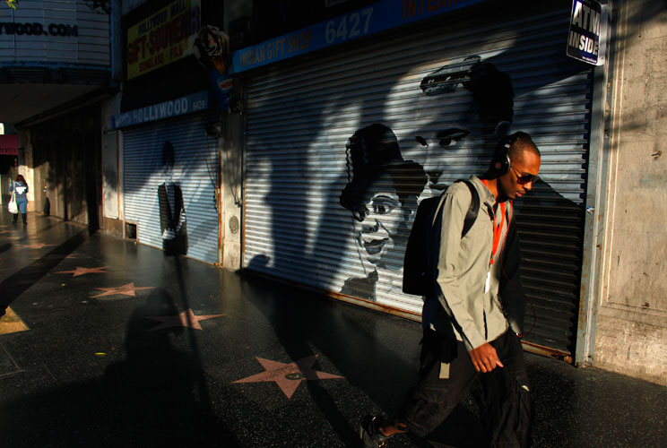 Pedestrians walk past closed shops along Hollywood Boulevard.