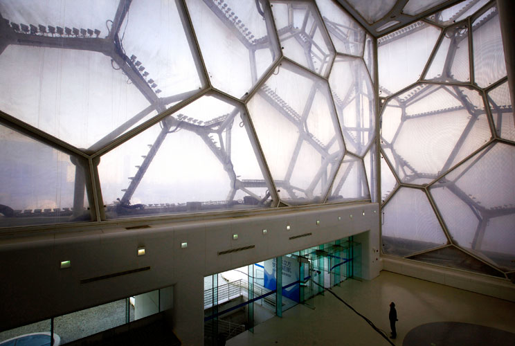 A worker looks up at the honeycomb-shaped walls of the National Aquatics Centre, also known as the "Water Cube", which was the venue for the 2008 Beijing Olympic Games swimming and diving competitions in Beijing March 27, 2012. The gigantic infrastructure