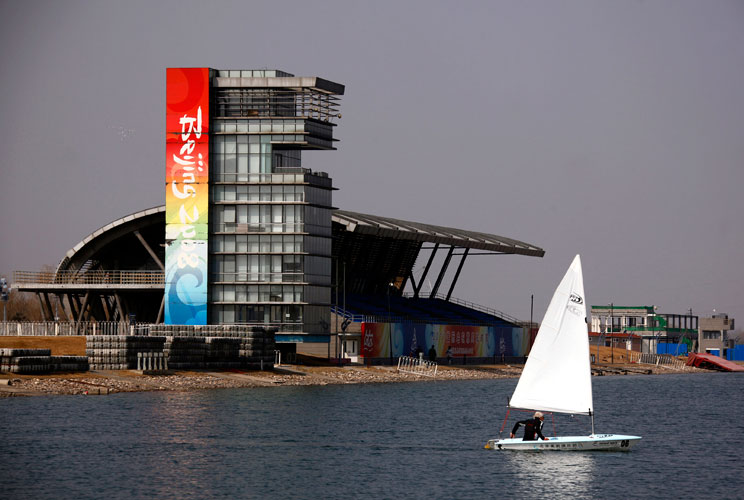 A boat sails past a stand and observation tower at the deserted former venue for the 2008 Beijing Olympic Games rowing competition, located on the outskirts of Beijing March 27, 2012. The gigantic infrastructures built for the Beijing Olympics, namely the