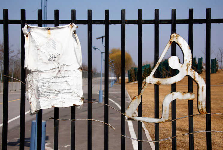 A weathered notice is seen on the main gate to the deserted and unmaintained former venue for the rowing and kayaking competitions of the 2008 Beijing Olympic Games, located on the outskirts of Beijing March 27, 2012. The gigantic infrastructures built fo