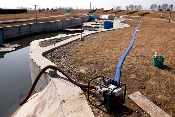 A pump is used to drain water for the surrounding plants from the deserted and unmaintained former course for the kayaking competition of the 2008 Beijing Olympic Games, located on the outskirts of Beijing March 27, 2012. The gigantic infrastructures buil