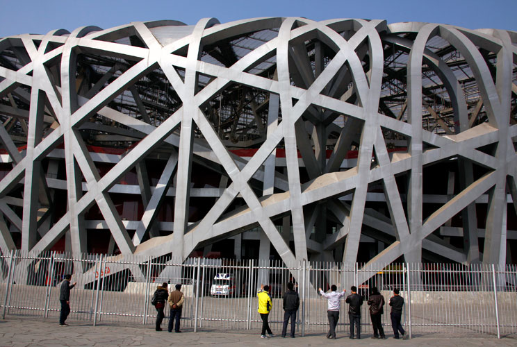 Chinese tourists look through a security fence at the National Stadium, also known as the "Bird's Nest", which was the venue for the athletics and the opening and closing ceremonies of the 2008 Olympic Games in Beijing March 23, 2012. The gigantic infrast