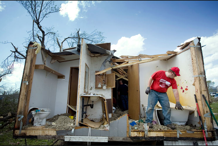 Tim Crom picks up debris from a damaged home on April 15. 