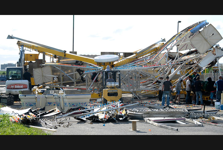 Workers try to dismantle and untangle a tornado-damaged Ferris wheel that flipped over in southern Wichita.