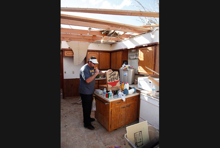 Shane Semmel takes a dinner break as he helps clean up a friend's home that was destroyed by a tornado.