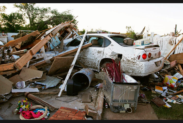 A car is covered in debris following a tornado that caused major damage to Woodward.