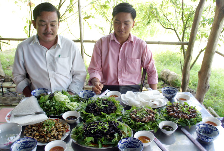 Crickets breeder Le Thanh Tung (R) and driver Nguyen Trong Thanh look at a table which displays cooked crickets at a farm in Ho Chi Minh city in 2006. 