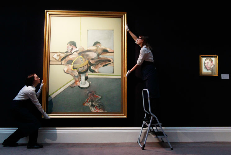 Francis Bacon's painting, "Figure Writing Reflected in Mirror," gets careful attention from employees of Sotheby's auction house in London, April 13, 2012. The painting, estimated at $40 million, will be auctioned in New York City on May 9.   