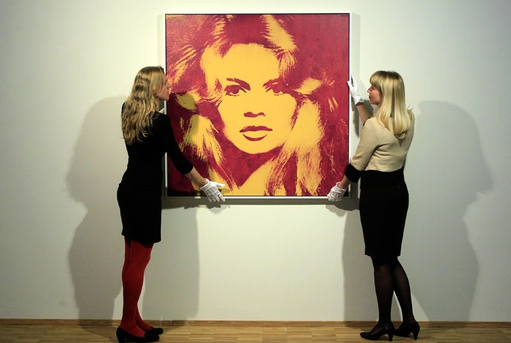 Sotheby employees adjust an acrylic and silkscreen ink-on-canvas portrait of French actress Brigitte Bardot from 1974 by American artist Andy Warhol (1928-1987) in Zurich, April 17, 2012. The picture, with an estimated worth of $3,754,000 to $6,339,000, i