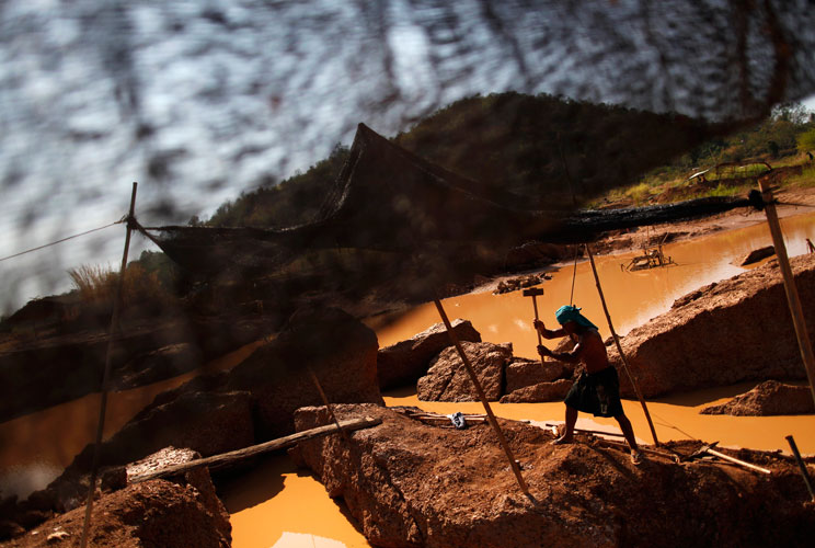 Boonchu Tiengtan breaks stones at a primitive gold mine in Panompa near Phichin February 17, 2011. A group of Thais use primitive tools and methods to extract gold from self-run mines near the country's biggest and most modern Chatree gold mine. A family 