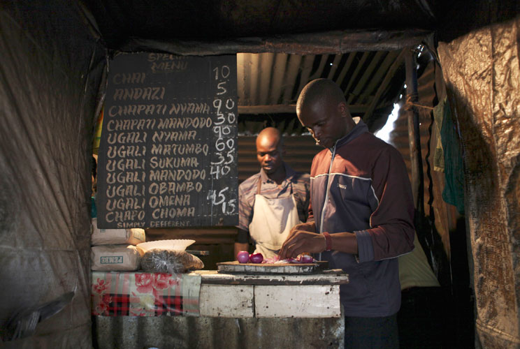 Denis Onyango Olang, (R), a 26 year-old assistant cook, prepares food in a dimly lit kitchen at a hotel in Nairobi's Kibera slum in the Kenyan capital April 30, 2012. Onyango Olang studied statistics and chemistry at Jomo Kenyatta University of Agricultur