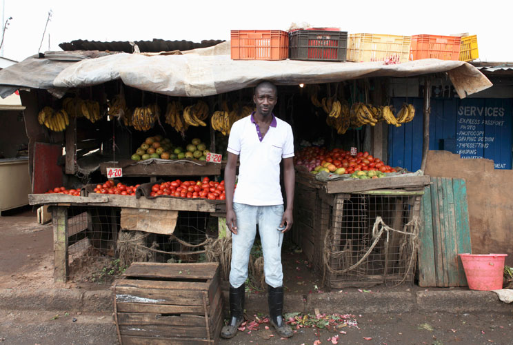 Karl Moi Okoth, a 27 year-old vegetable and fruit seller, poses for a picture in front of his makeshift shop in Nairobi's Kibera slum in the Kenyan capital April 30, 2012. Okoth studied psychology and chemistry at Day Star University where he received a d