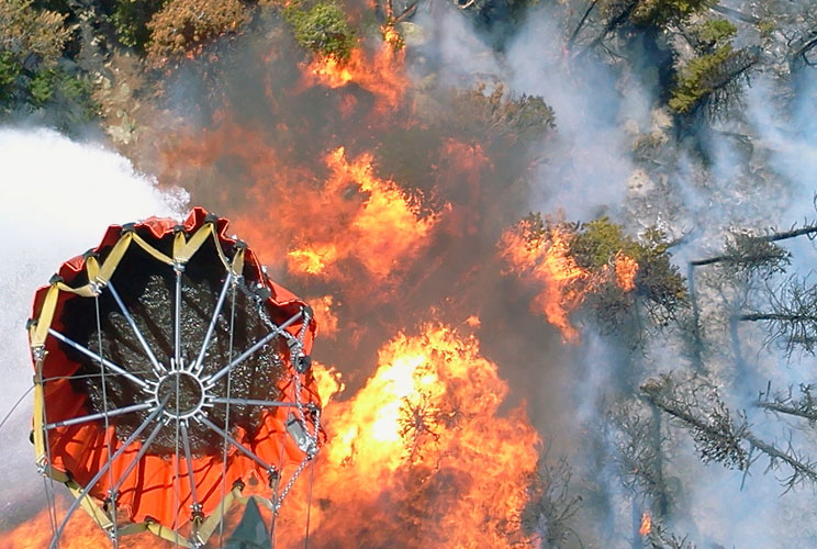 Nebraska National Guard crewmembers of an aviation battalion dump water from a Bambi bucket onto flames of the High Park fire west of Fort Collins, Colorado. The blaze, which started on June 9, was caused by a lightning strike and has torched over 65,000 