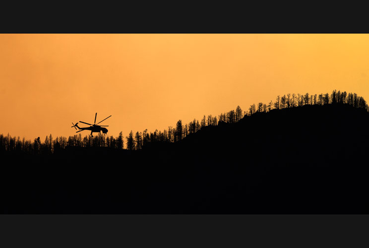 A helicopter hovers over a hilltop after dropping water to combat the Waldo Canyon blaze in Colorado Springs, July 1, 2012. Residents began returning to charred areas of Colorado Springs on Sunday after the most destructive wildfire in state history force