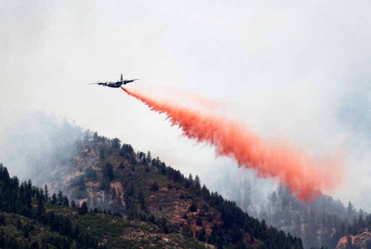 A C-130 military cargo plane drops thousands of gallons of retardant on the Waldo Canyon fire west of Colorado Springs, June 26, 2012. A fast-growing wildfire in Colorado forced 11,000 people from their homes at least briefly and threatened popular summer