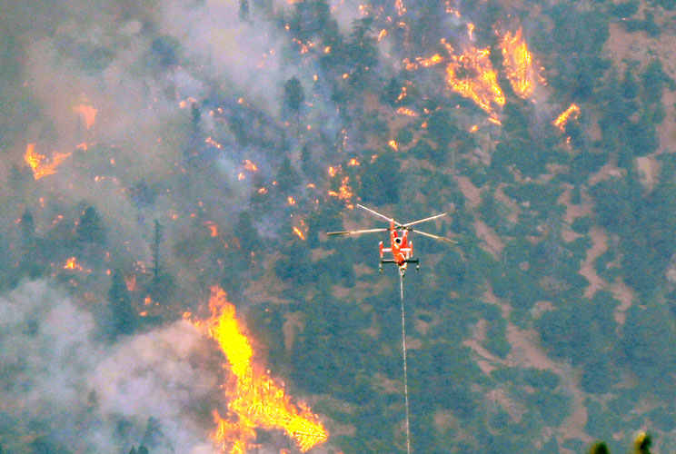 A firefighting helicopter approaches the Waldo Canyon fire, west of Colorado Springs, June 26, 2012. A raging wildfire near some of the most visited tourist areas in the state took a turn for the worse on Tuesday as hot winds pushed flames north, promptin