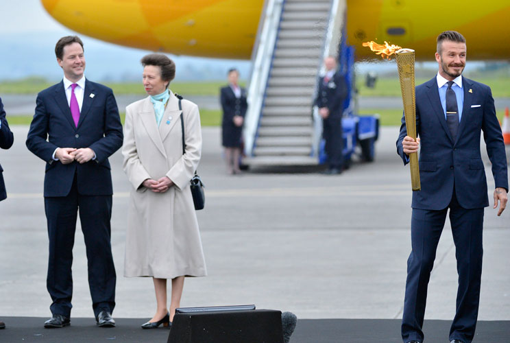 British soccer player and London 2012 Olympic Games ambassador David Beckham (R) reacts after lighting the Olympic torch with a cauldron after arriving at RNAS Culdrose base near Helston in Cornwall, south west England May 18, 2012. The London 2012 Olympi