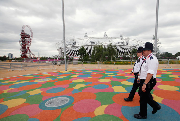 Police officers walk past the Olympic Stadium, in the Olympic Park, in Stratford, east London, July 17, 2012. The head of G4S admitted his management of the London Olympics staffing scandal had embarrassed the British government and left the world's bigge