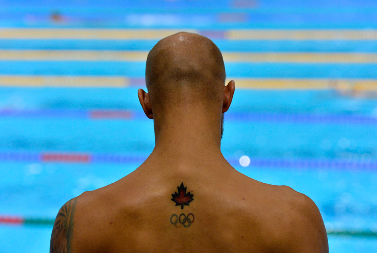 A tattoo of a maple leaf and the Olympic rings is seen on the back of Canada's Brent Hayden as he attends a training session at the main pool of the Aquatics Centre before the start of the London 2012 Olympic Games in London July 25, 2012.  REUTERS/Toby M