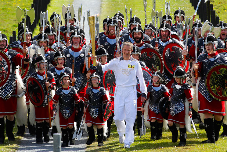 Torch bearer Mathew Cox (C) walks with the London 2012 Olympic torch while surrounded by the Jarl vikings in Lerwick in the Shetland Islands, Scotland June 10, 2012. The Jarl vikings provided a guard of honour during the torch relay on the islands, which 