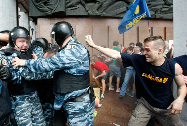 An opposition activist attacks riot police during a rally to protest against a Russian language bill passed by parliament in Kiev July 4, 2012. Hundreds of protesters clashed with riot police in central Kiev and Ukraine's parliament speaker offered to res